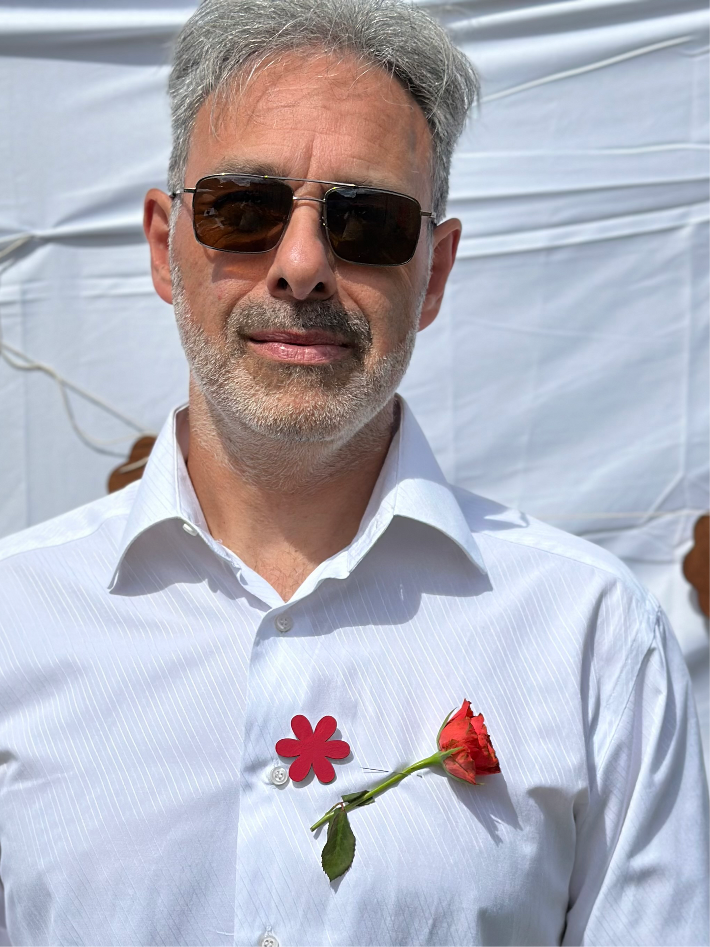 hommr portant sur sa chemise un pins en forme de fleur de couleur rose
