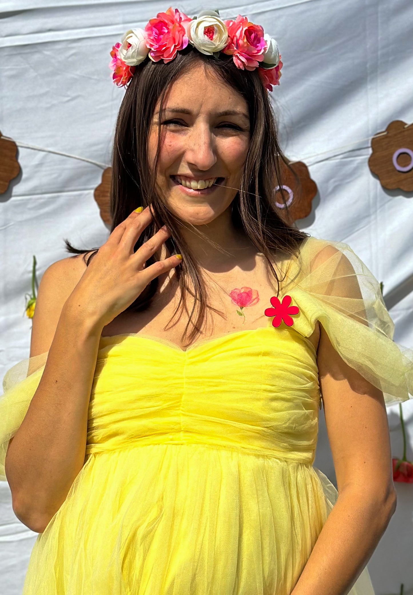 femme enceinte portant une robe jaune et un pins en forme de fleur rose