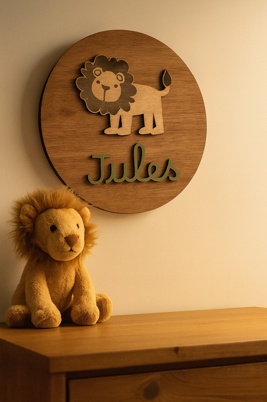 Plaque personnalisée en bois avec lion et prénom « Jules » fixée au mur au-dessus d’une commode en bois clair, accompagnée d’une peluche lion, dans un éclairage doux créant une atmosphère cosy dans une chambre de bébé.