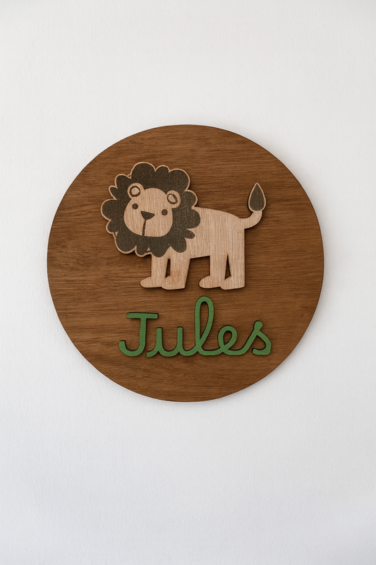 disque en bois vernis en chêne personnalisé avec un petit lion en bois fixé et le prénom "Jules" peint en vert olive et fixé sur le disque qui est accroché à un mur blanc
