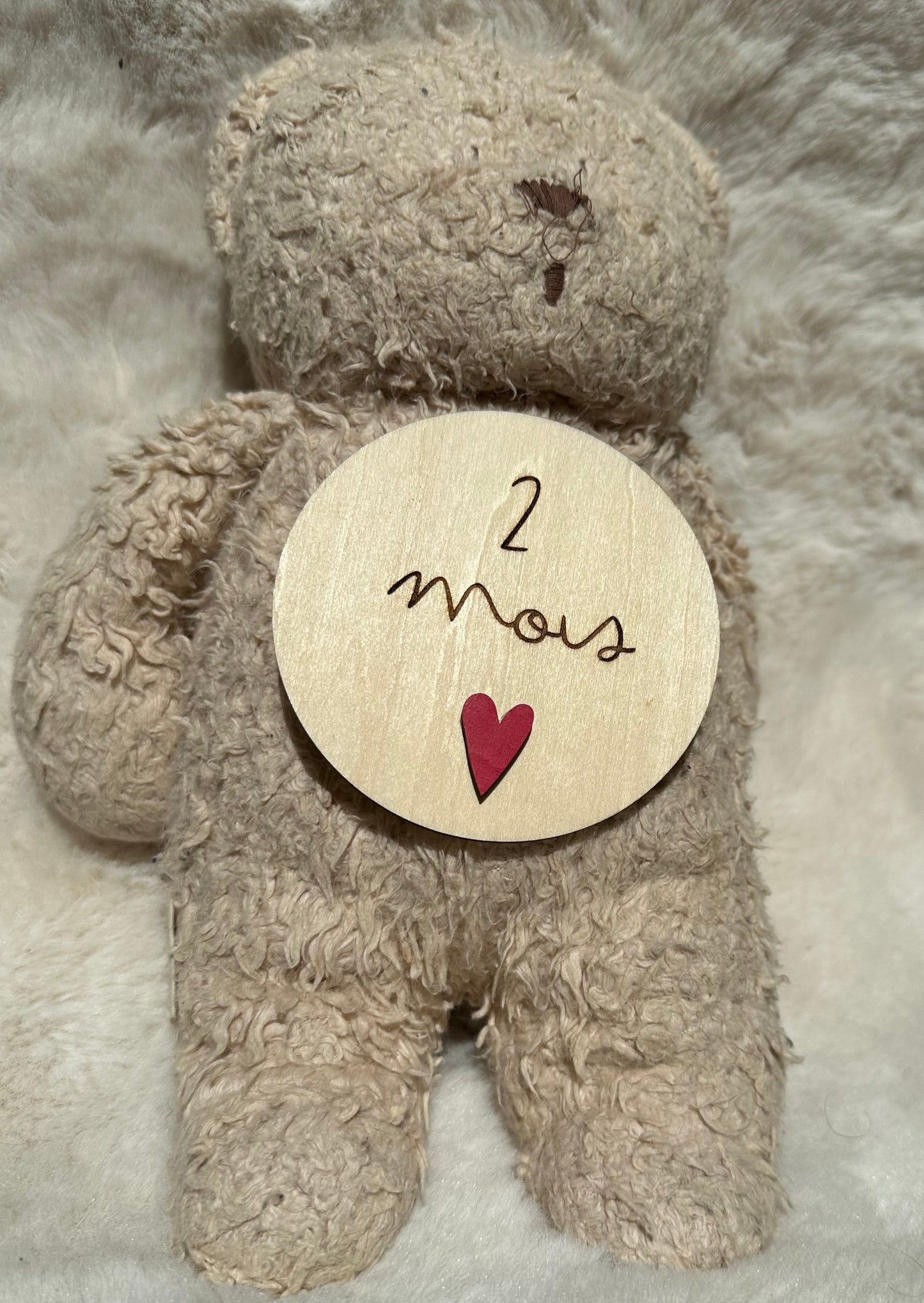 carte étape " 2 mois " en bois, coeur rose posée sur ours en peluche