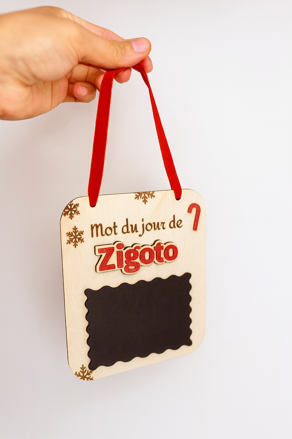une pancarte en bois avec une ardoise pour que le lutin farceur puisse écrire un message chaque matin. Suspendu avec un ruban au sapin. Prénom du lutin en plexi rouge personnalisé, ici "zygoto"