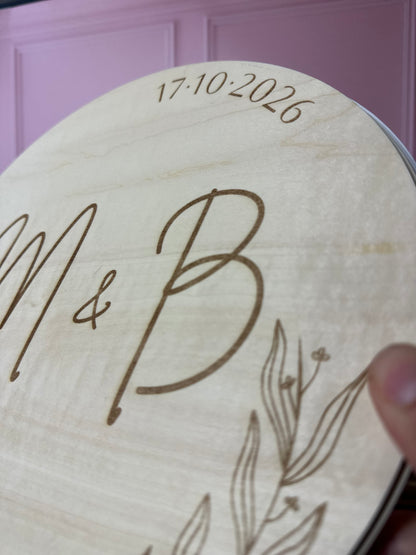 détails du livre d'or en bois gravé avec les initiales des mariés (M & B) et la date du mariage. le livre d'or personnalisé est rond est relié par une cordelette.