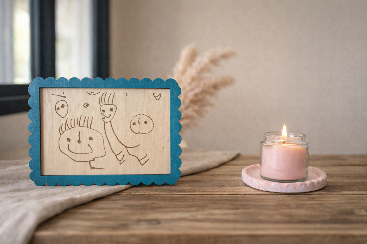 dessin de bonhommes encadré en bois et posé sur une table en bois prêt d'une bougie : idée cadeau fête des mères unique