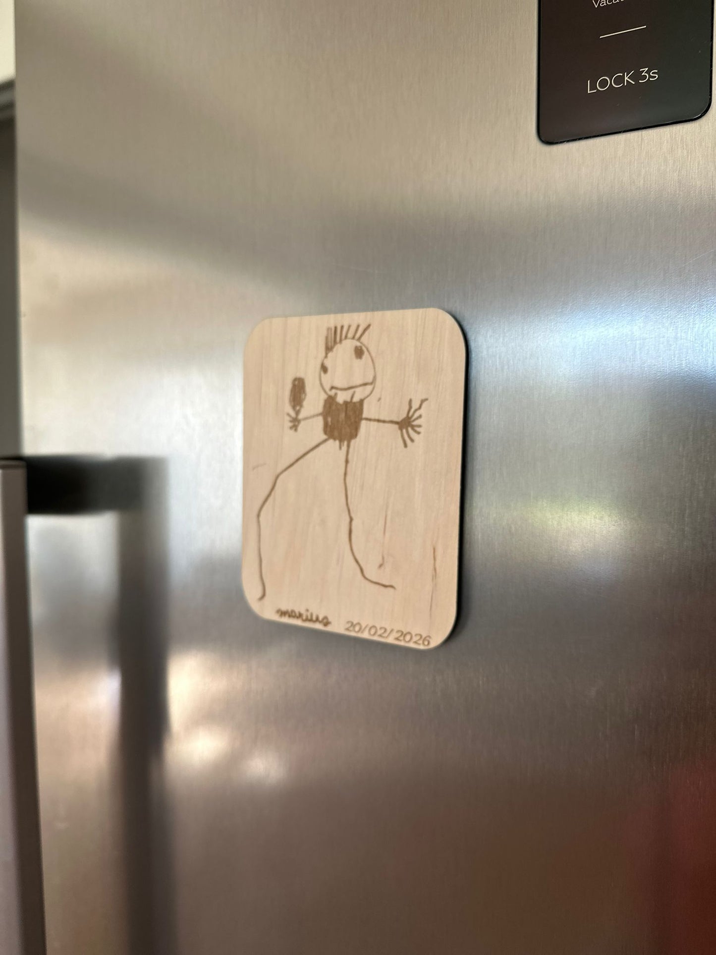 le dessin de votre enfant reproduit sur un magnet en bois et fixé sur le frigo gris