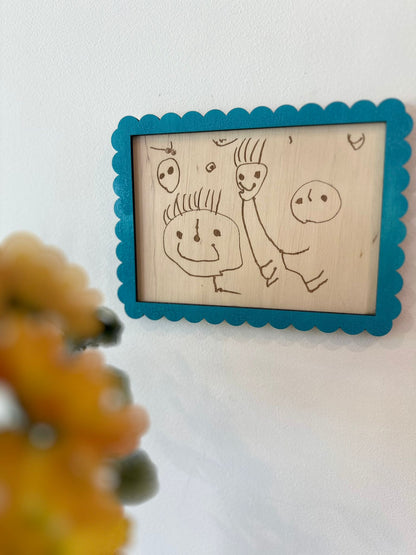 un dessin de bonhommes réalisé par un enfant gravé sur une plaque en bois et encadré en bleu