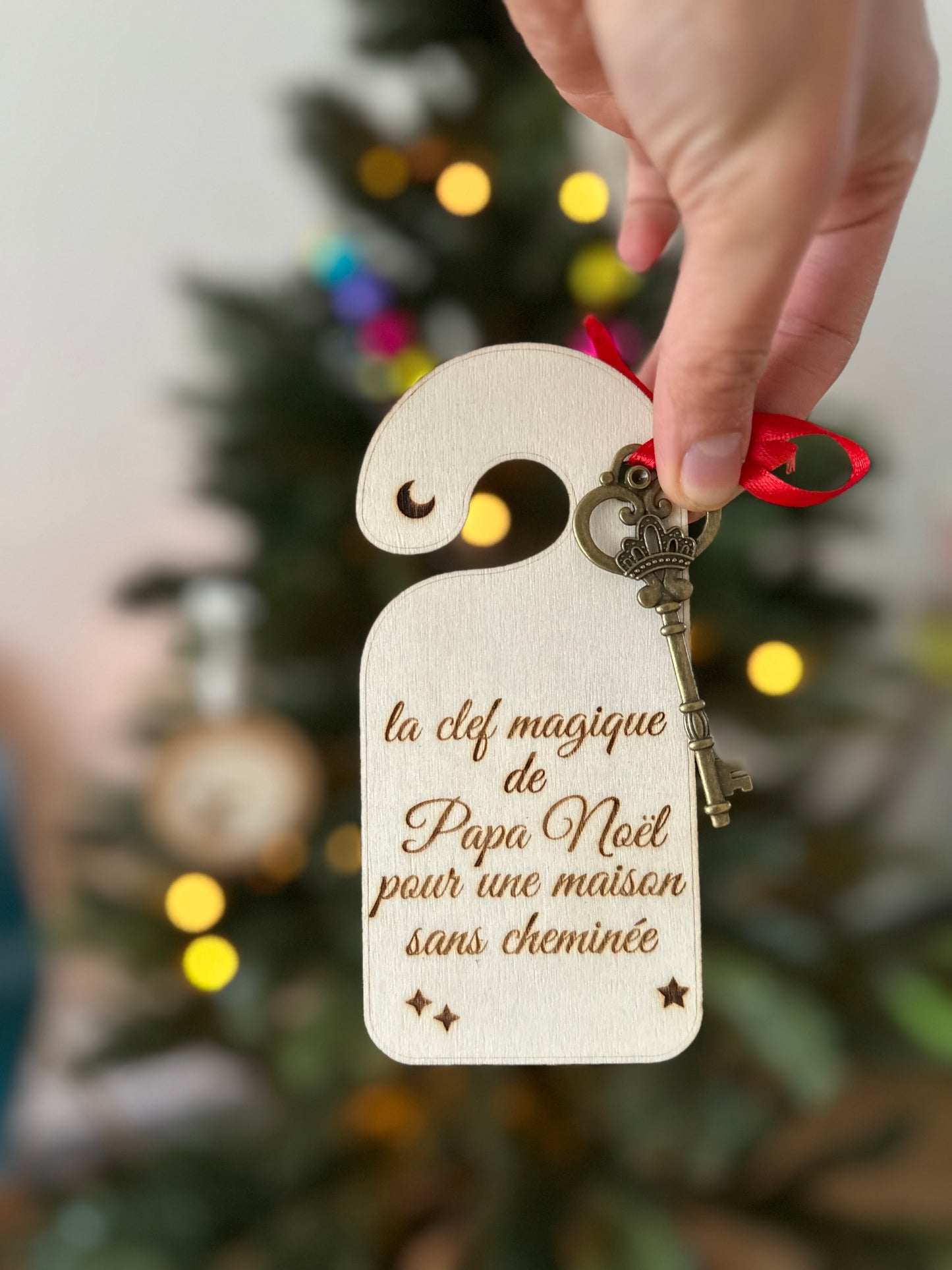  magique de Papa Noël en bois, tenue entre les doigts devant un sapin lumineux, avec une clé dorée attachée par un ruban rouge, pour les maisons sans cheminée.