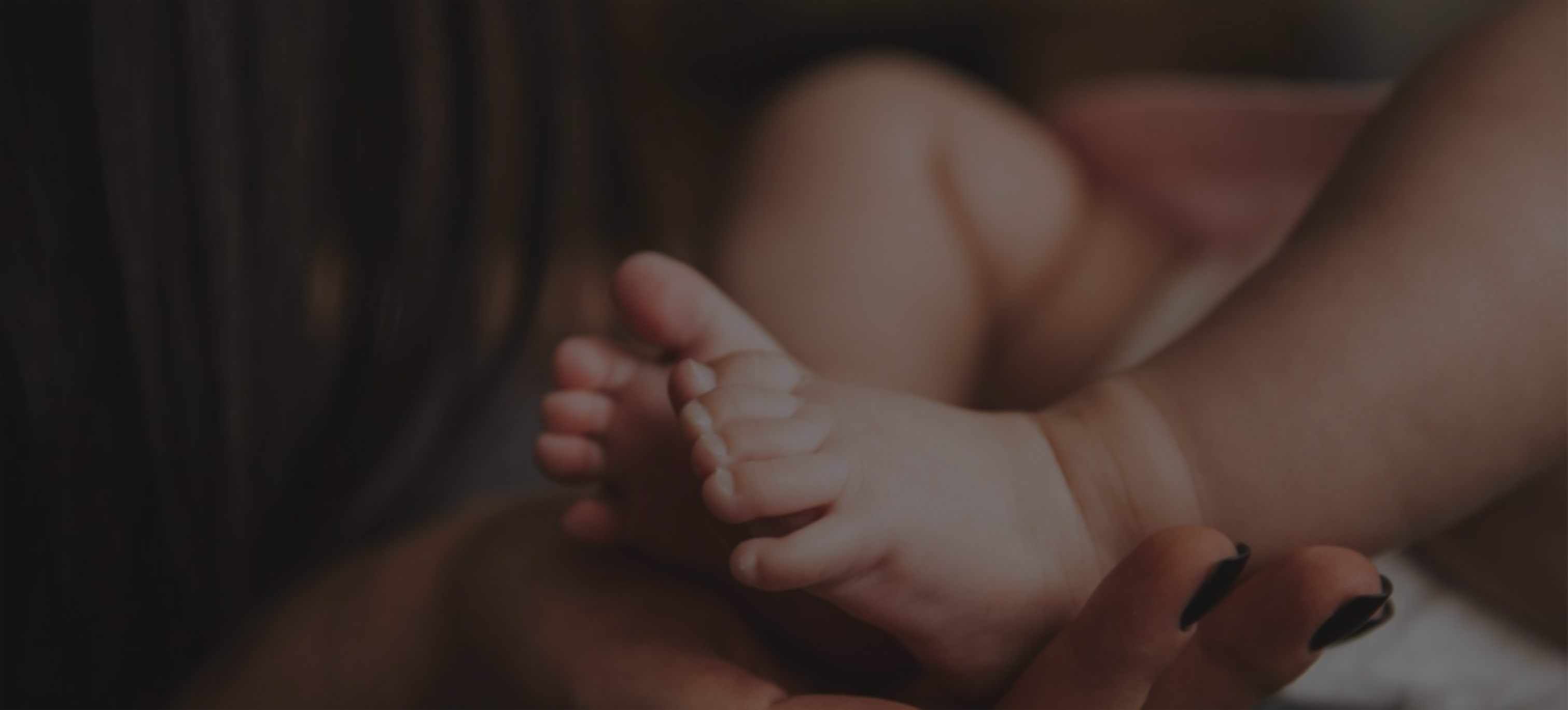 pieds d'un bébé porté par une main de femme