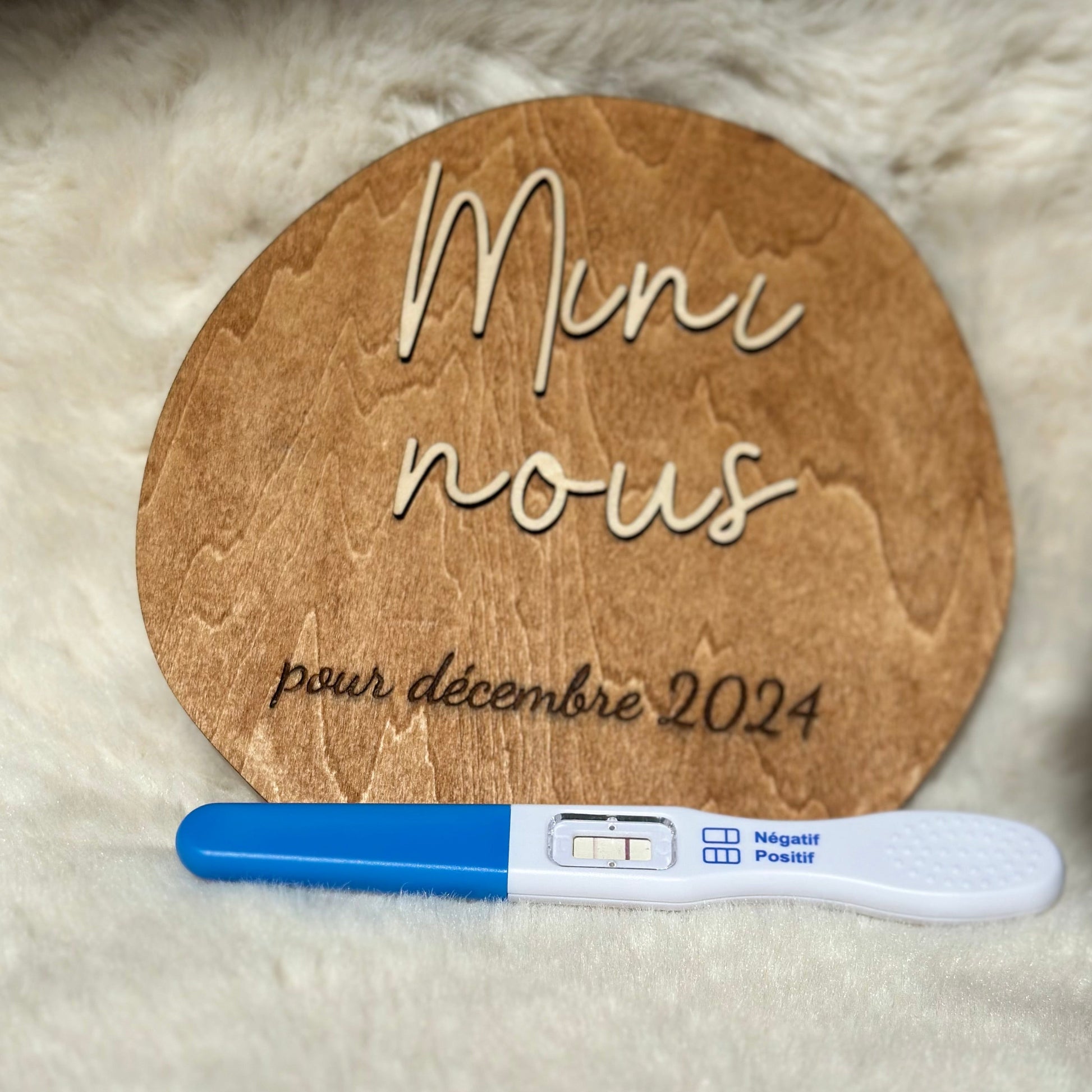 disque en bois annonce "mini nous" pour décembre 2024 et un test de grossesse positif