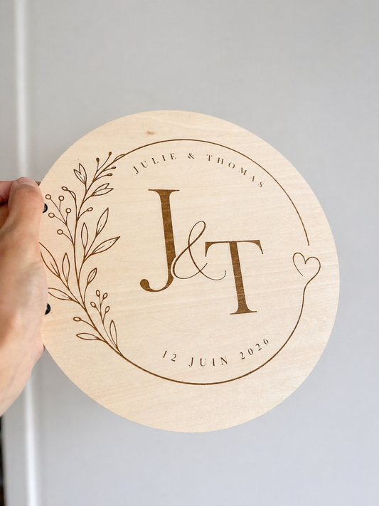 livre d'or en bois gravé avec les initiales, les prénoms des mariés et la date du mariage. le livre d'or personnalisé est rond est relié par une cordelette.