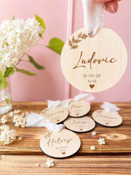 médaillons invités mariage : marque-places en bois gravés avec prénoms des invités, initiales des mariés et date de la réception. Un souvenir parfait à commander en lot