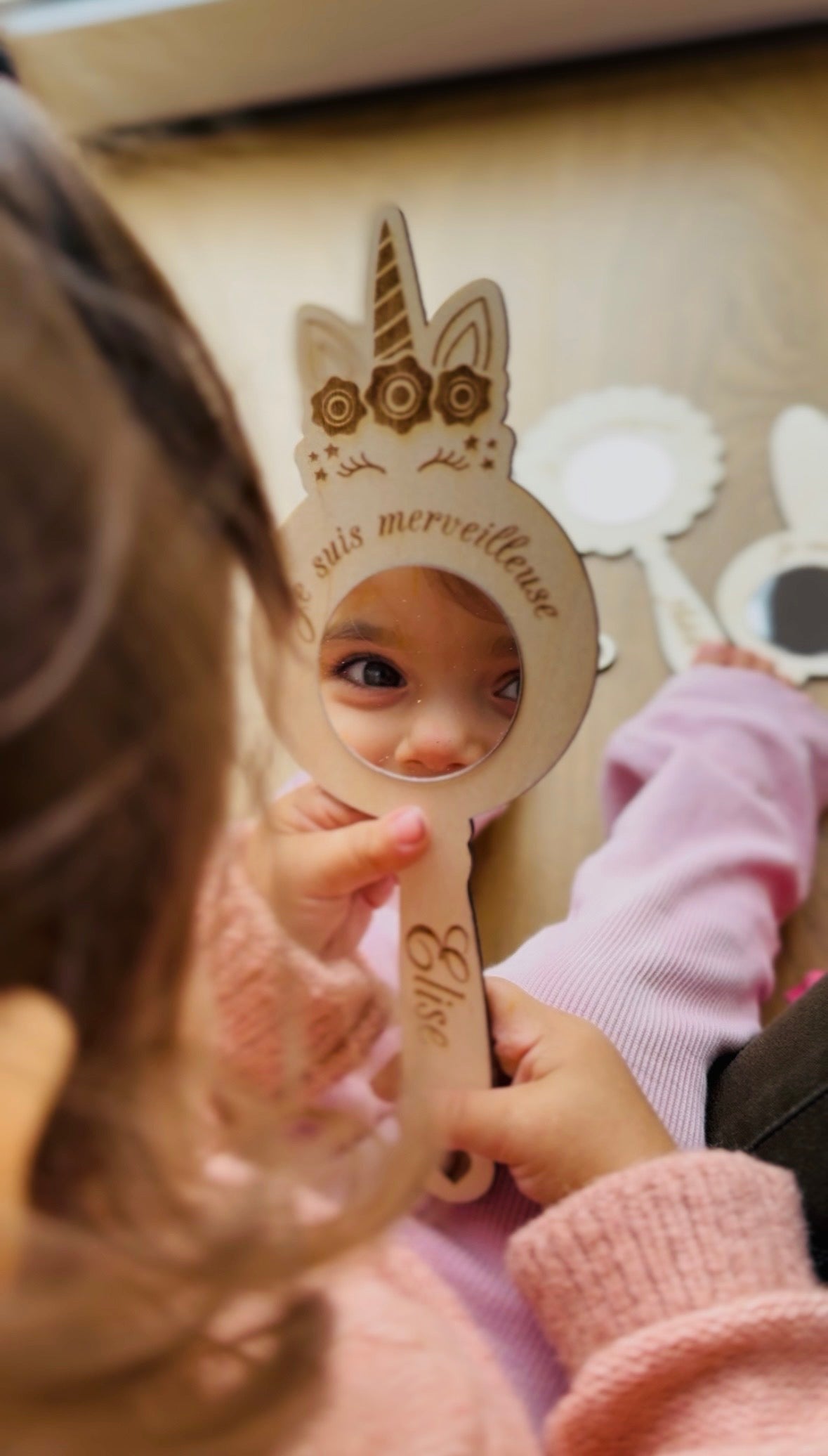 petite fille observant son reflet dans un miroir licorne où il est gravé "je suis merveilleuse" et son prénom "Elise", 
