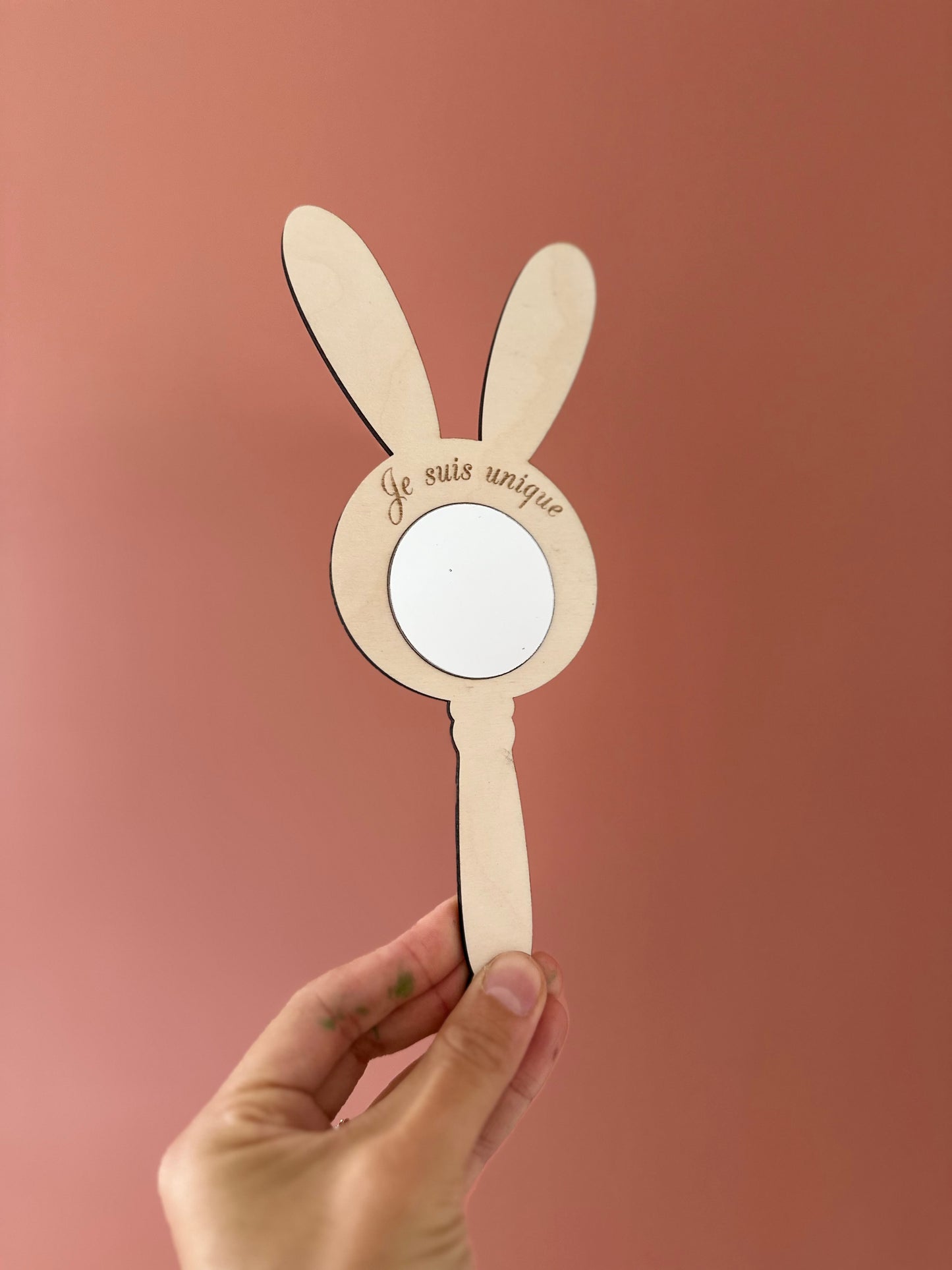miroir mantra gravé "je suis unique" et tenue en face d'un mur terracota