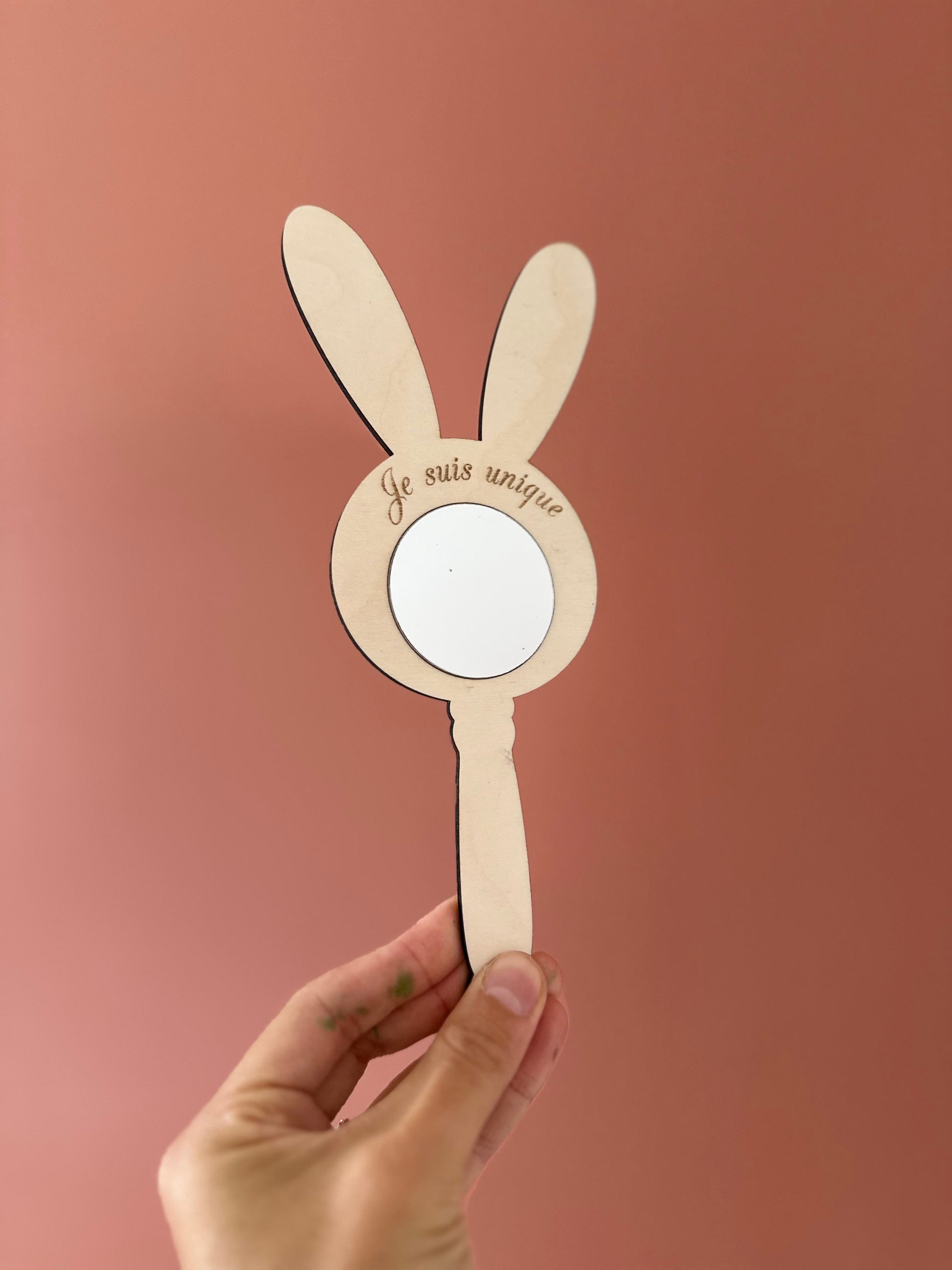 miroir mantra gravé "je suis unique" et tenue en face d'un mur terracota