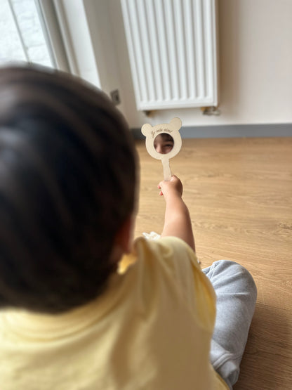 petit garçon de dos se regarde dans un miroir en forme d'ours où il est gravé "je suis aimé"