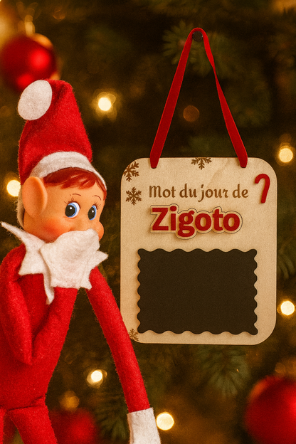 une pancarte en bois avec une ardoise pour que le lutin farceur puisse écrire un message chaque matin. Suspendu avec un ruban au sapin. Prénom du lutin en plexi rouge personnalisé, ici "zygoto"