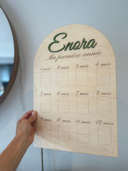 pancarte en bois ma première année personnalisée avec le prénom de bébé peint en vert "Enora" et 12 emplacements pour les photos des 12 premiers mois de bébé