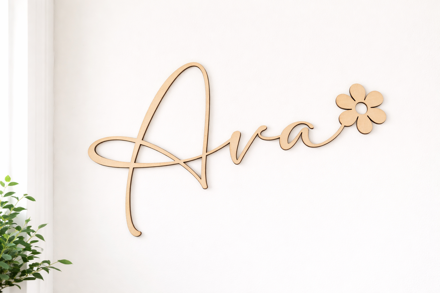prénom en bois découpé au laser dans une police élégante et moderne : Ava, le prénom se termine par une fleur type marguerite. Le prnéom est fixé sur un mur blanc, à côté d'une fenêtre; IL Y A UNE PLANTE GRASSE SUR LE CÔTÉ