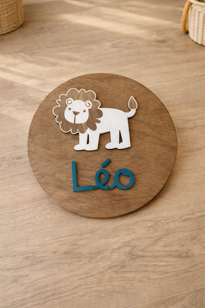 disque en bois personnalisé avec le prénom Léo peint en bleu océan et un lion en bois fixé au dessus pour une décoration de chambre unique. lE DISQUE EST POSÉ SUR UNE COMMODE en bois, prêt de 2 paniers en osier