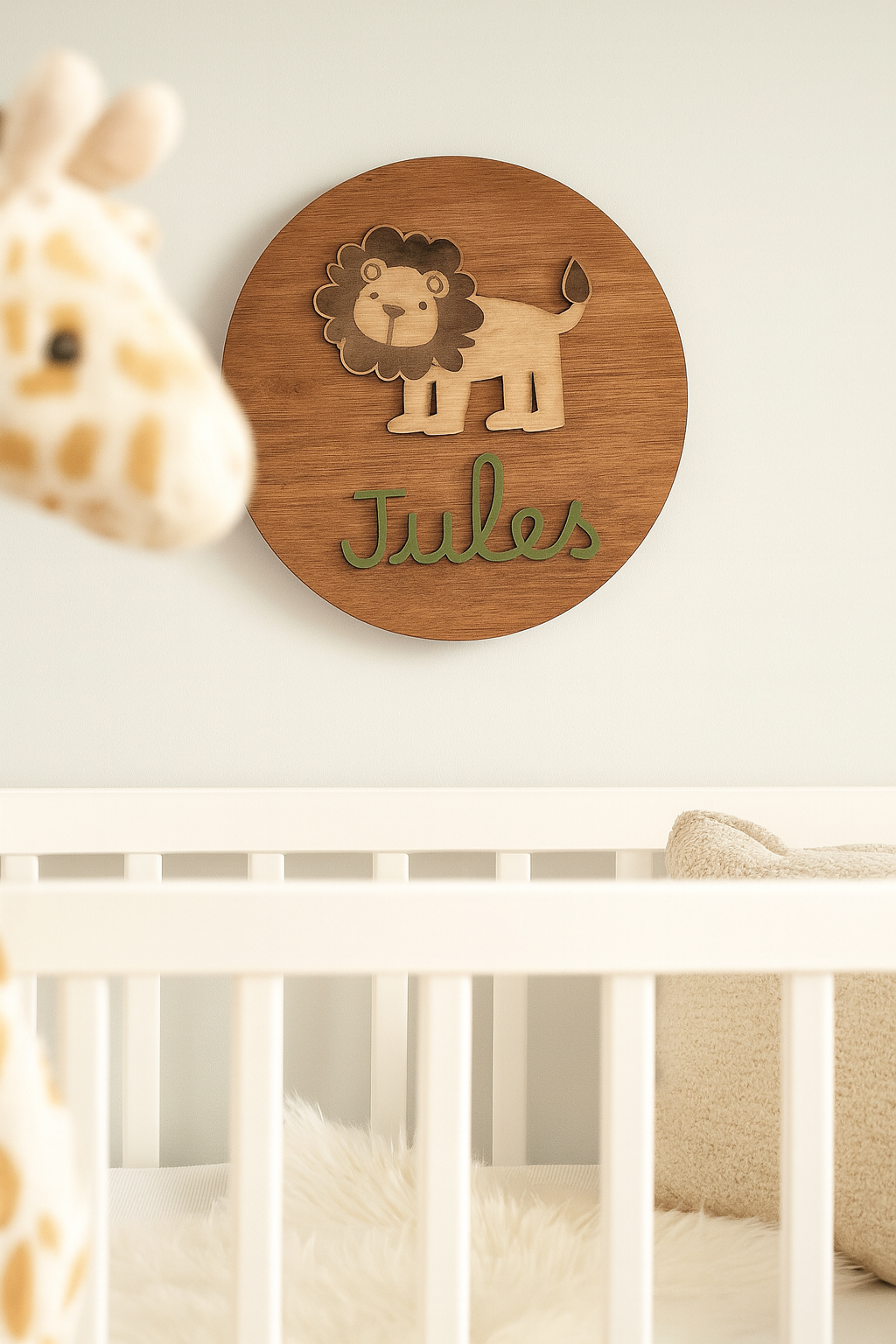 Décoration murale personnalisée en bois représentant un lion mignon et le prénom « Jules » en lettres vertes, accrochée au-dessus d’un lit bébé blanc dans une chambre douce et lumineuse, ambiance naturelle et cocooning.