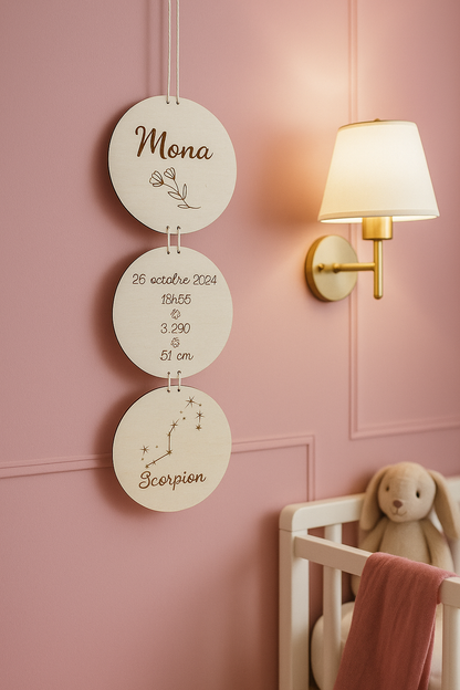 Suspension de naissance avec les infos de bébé : son prénom, sa date de naissance, son heure de naissance, sa taille et son poids de naissance, son signe du zodiaque. lA SUSPENSION est suspendue prêt d'un berceau 