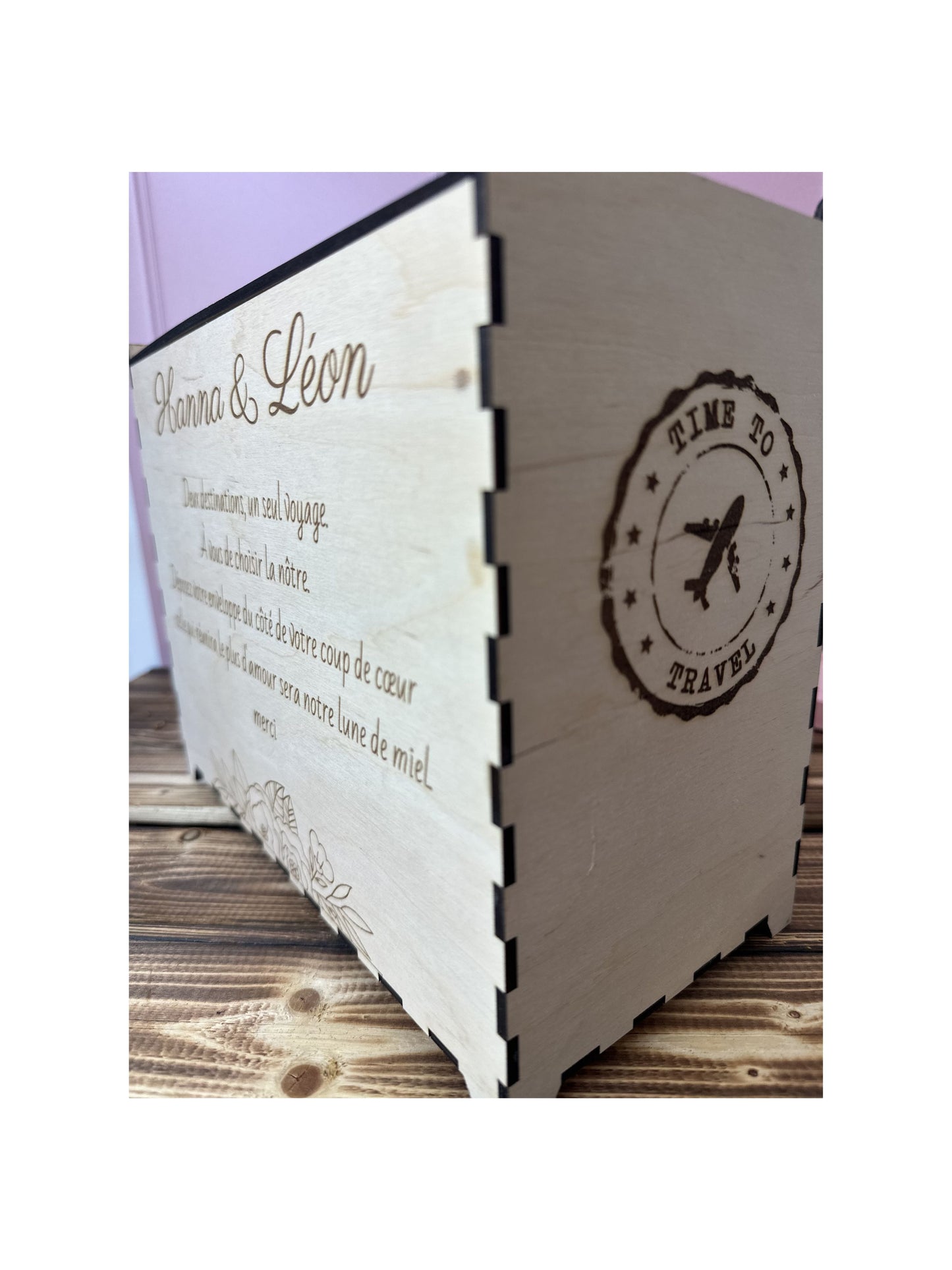 urne en bois personnalisée pour le mariage d'Hanna & Léon avec un message personnalisé gravé dessus et zoom sur la tranche de l'urne : un tampon time to travel" gravé avec un avion au milieu