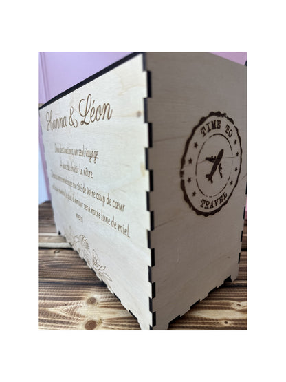 urne en bois personnalisée pour le mariage d'Hanna & Léon avec un message personnalisé gravé dessus et zoom sur la tranche de l'urne : un tampon time to travel" gravé avec un avion au milieu